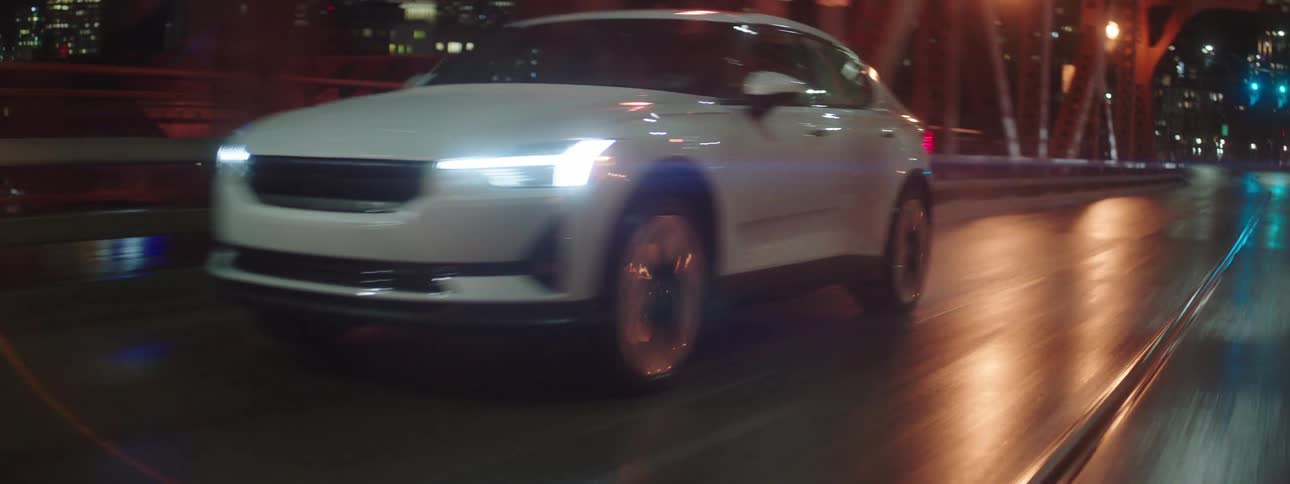 A white car drives on a bridge in the city at night