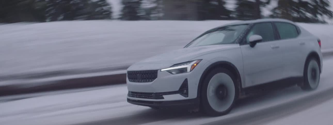 White sports suv car traveling along a snowy road and next to conifers on a cloudy day