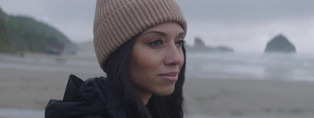 Portrait of a young woman with facial expression of happiness while standing in a natural environment on the beach sand