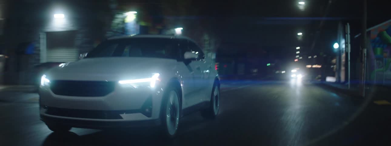 A white car driving on a city street at night