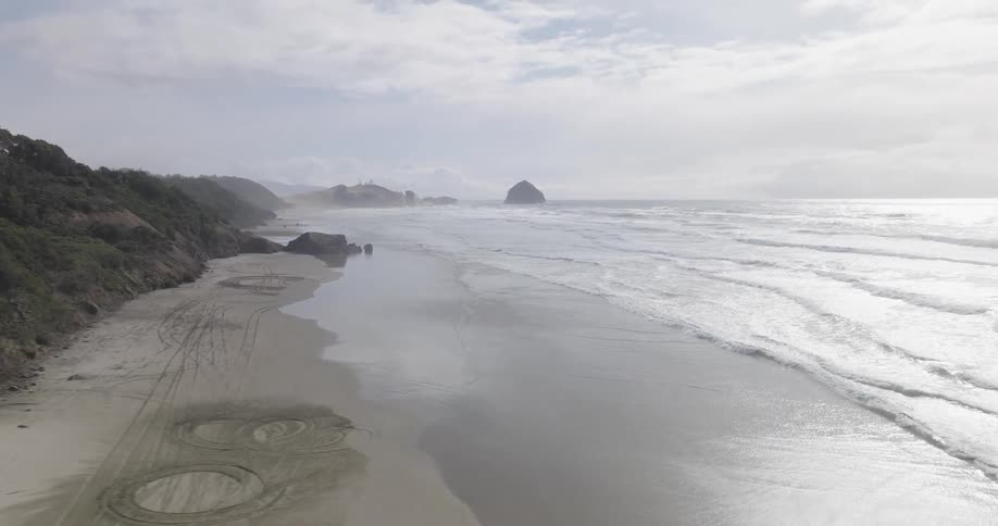 Aerial view of a beach with gentle waves next to the mountains