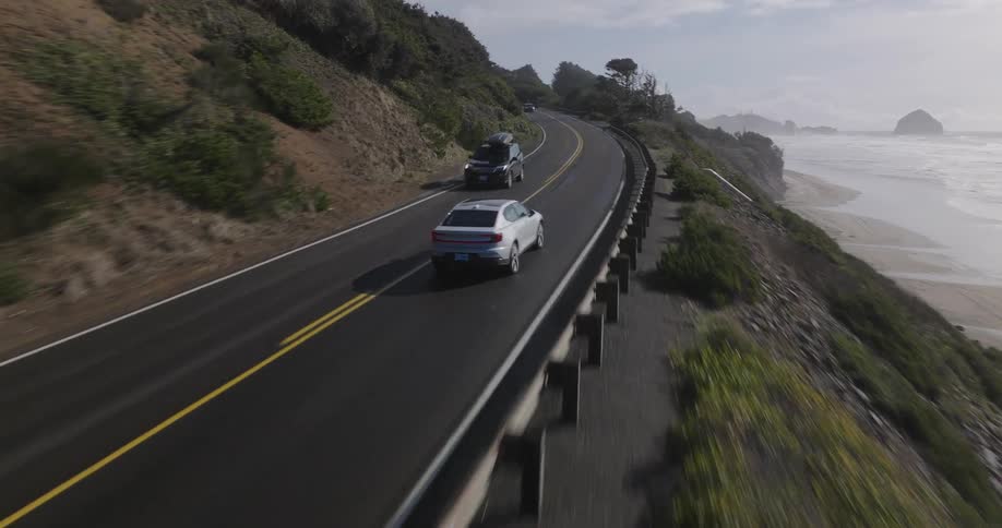 White suv car traveling on a highway next to a beach and mountains