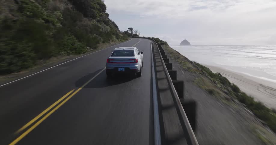 A car drives down a twolane highway next to the ocean beach