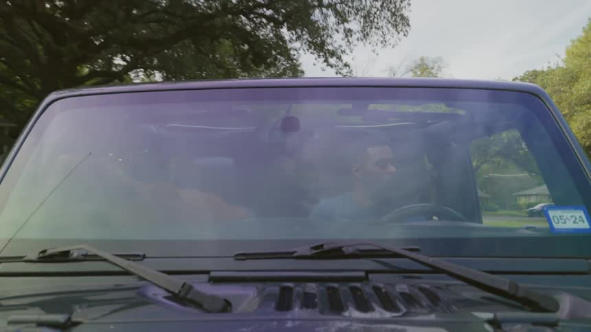A man and his dog cruise around a suburb in a vehicle