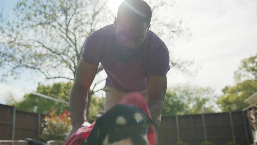 A man gives his dog a bath in the backyard