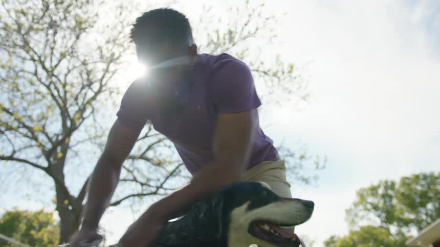 A man bathes his dog in the backyard on a sunny summer day