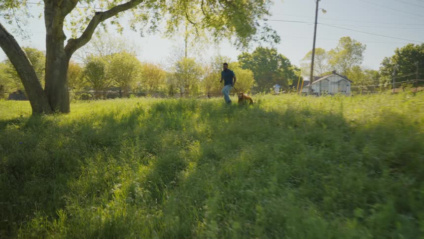 A man running with a dog on a field in the countryside