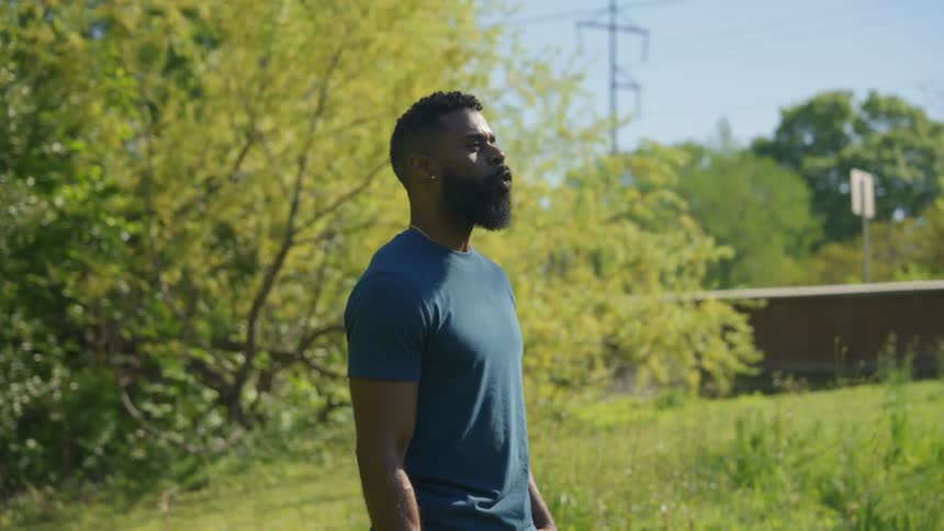 A young bearded man whistles to call his dog in the backyard
