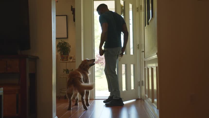 Man opening the door of his house and coming out with his golden retriever dog