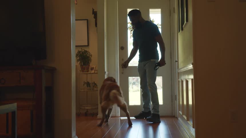 Man opening the door of his house and coming out with his golden retriever dog