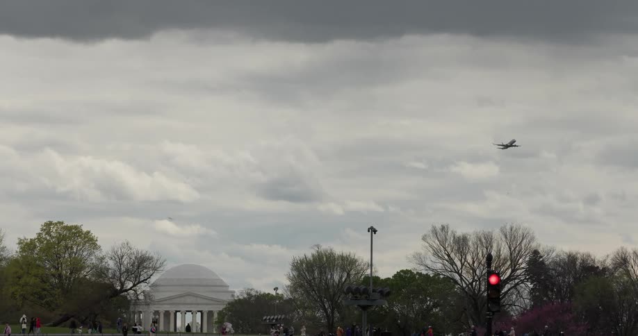 An airplane flies over the jefferson memorial in washington dc