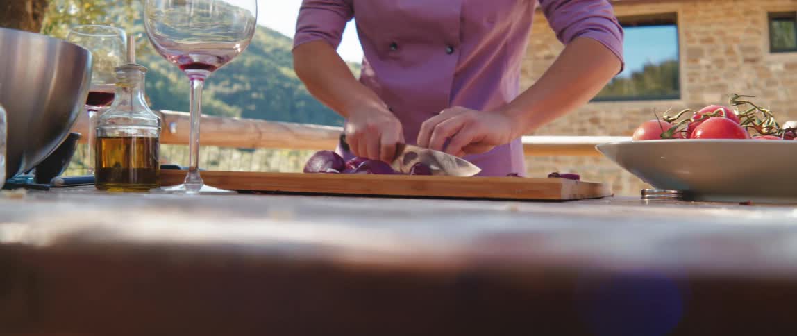 A chef is cutting onions on the balcony