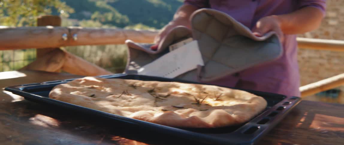 The chef serves a large naan on a tray