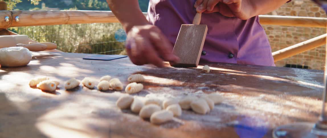 Woman hand placing pasta grains into a manual pasta mold