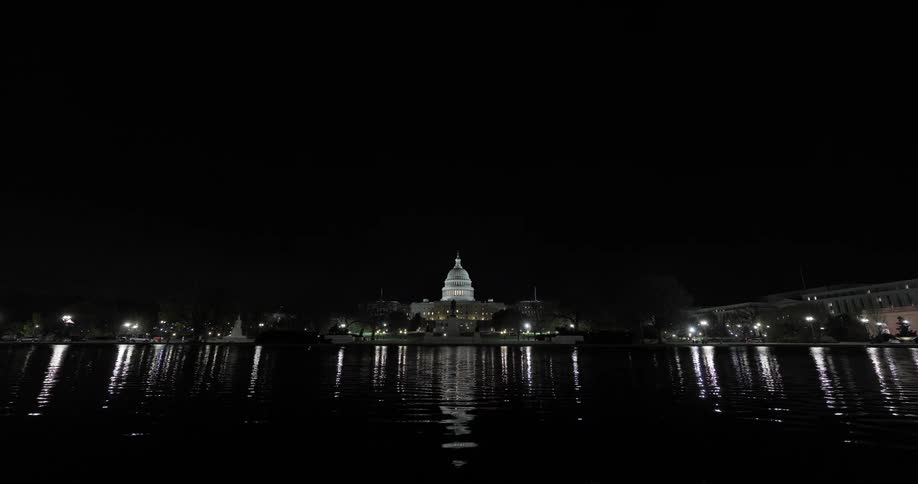 The united states capitol building reflected on the water at night