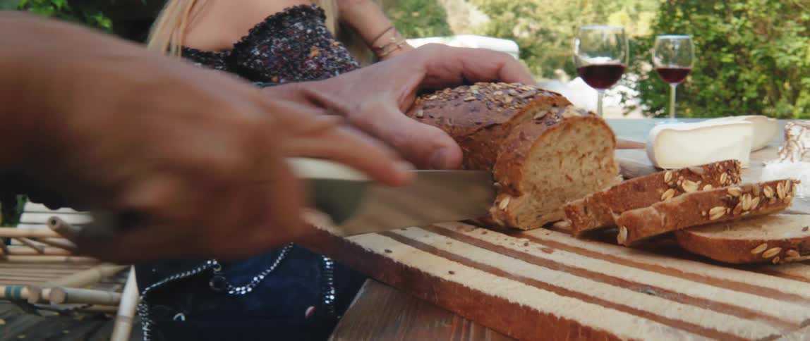 A person cuts bread on a tray outdoors