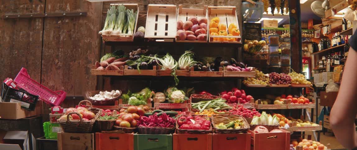 A variety of fresh vegetables and fruits in wooden crates at a market stall