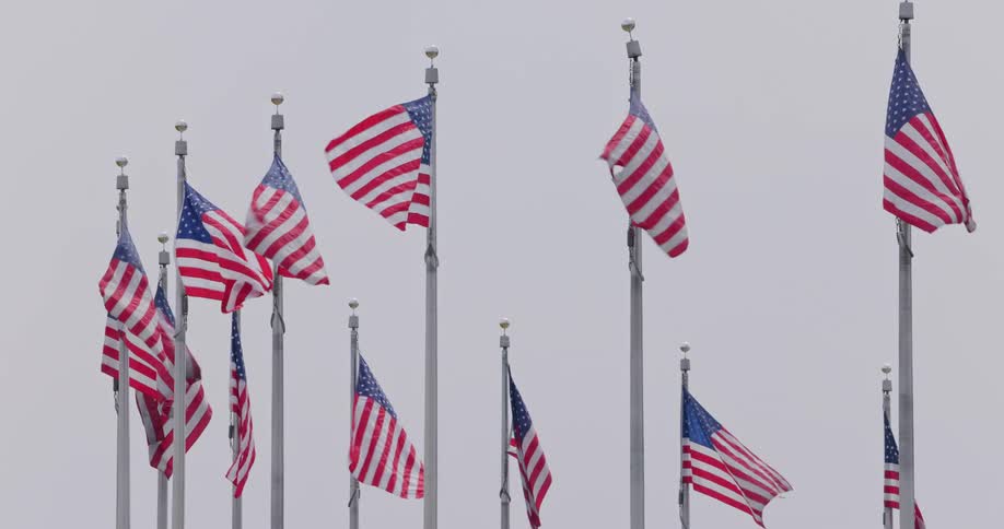 United states flags flying on flagpoles against a cloudy sky