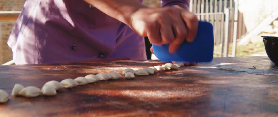 Woman hands with a spatula cutting pasta into grain shapes