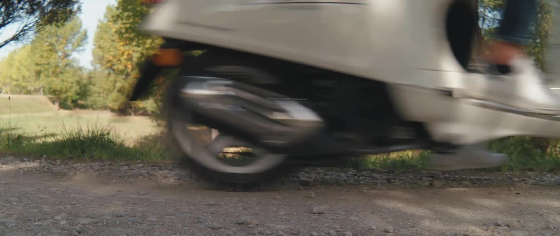 A person rides a scooter down a dirt road