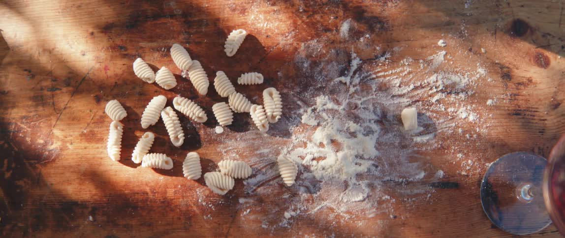 Woman hand picking up fresh pasta grains on a wooden table