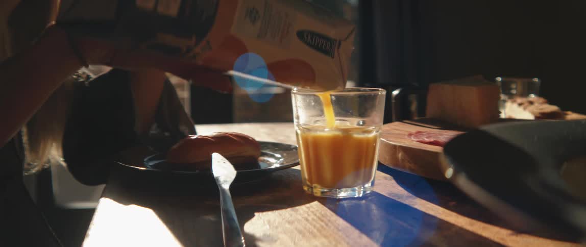 A person pours juice into a glass