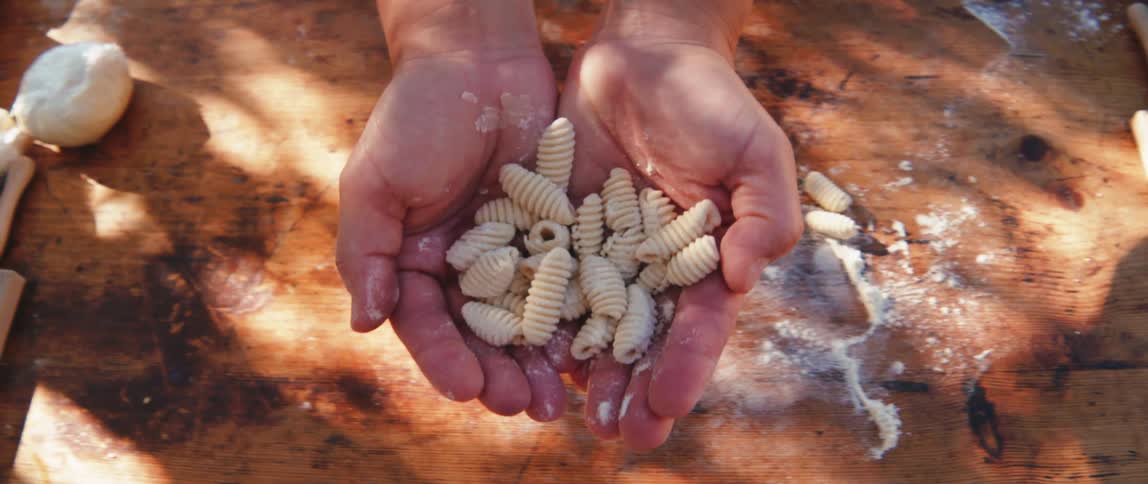 A woman holds pasta in her cupped hands