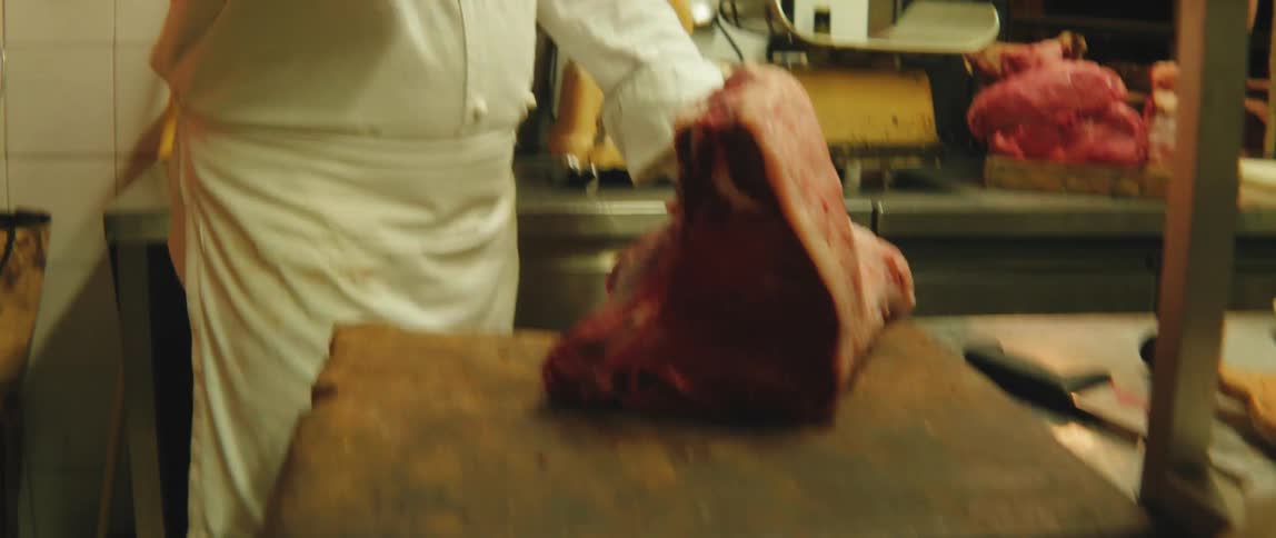 Hand of a butcher cutting a piece of meat with a special knife