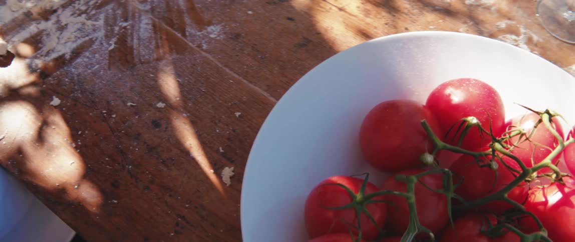 Shadow hands prepare food near a plate of tomatoes