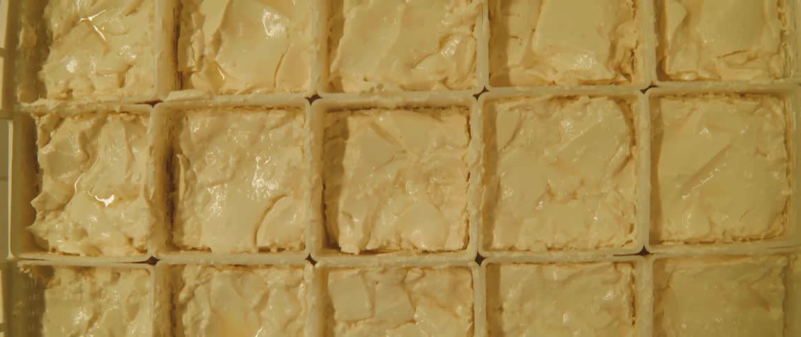 A stack of square containers filled with light yellow butter