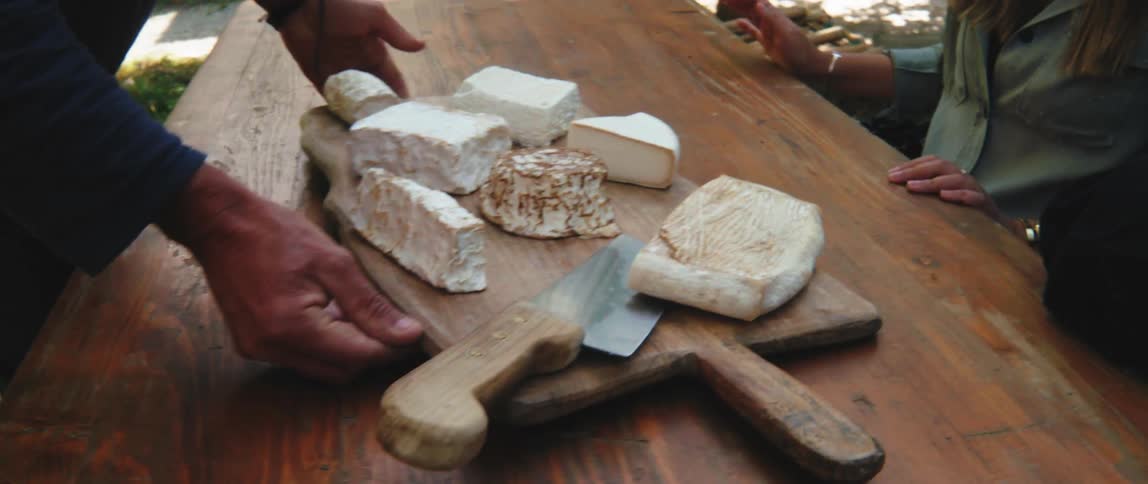 A restaurant worker serves a cheese tray to customers