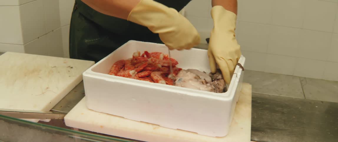 A person is storing shrimp and octopus in a fish market
