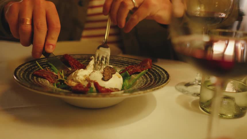 A person eating a dish with cheese and vegetables