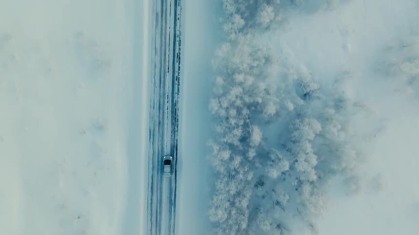 Vehicle drives along highway through snow covered countryside