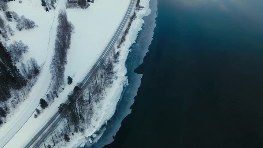 Aerial of a car on the snowy road and lake shore