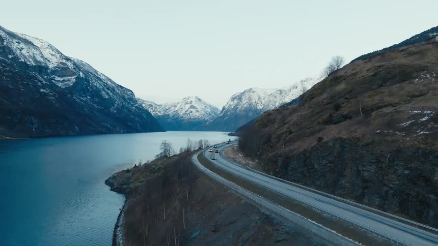 Traffic moves around the curves of mountain valley roads alongside an ice covered river