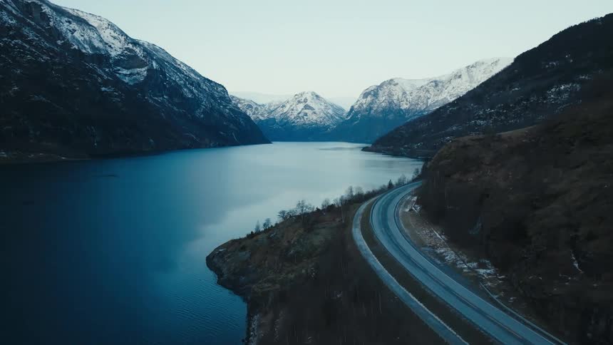 Aerial view of a road next to a river in the mountains