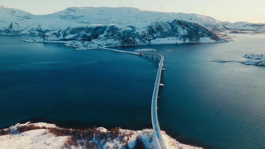 Aerial landscape view of a bridge over the sea connecting two mountain areas during dusk or dawn
