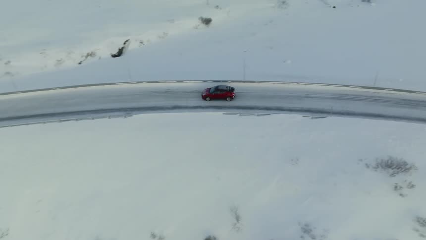 Red vehicle driving on a snowy road