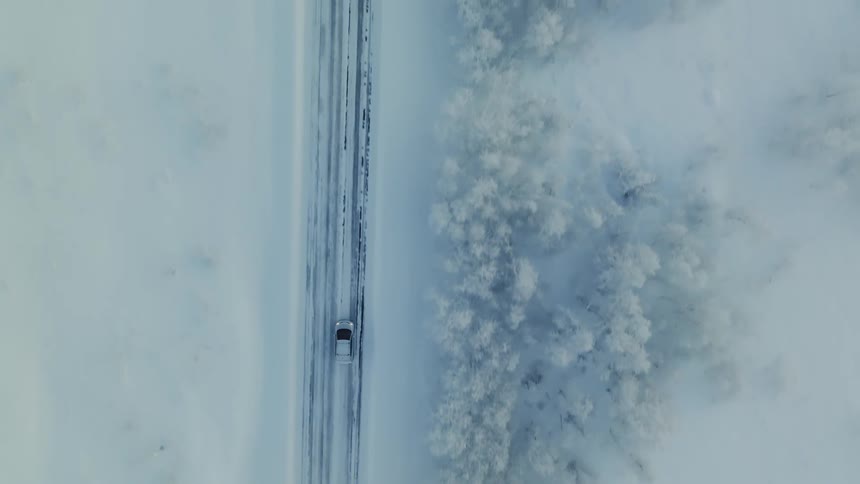 Vehicle drives through snow covered countryside during winter