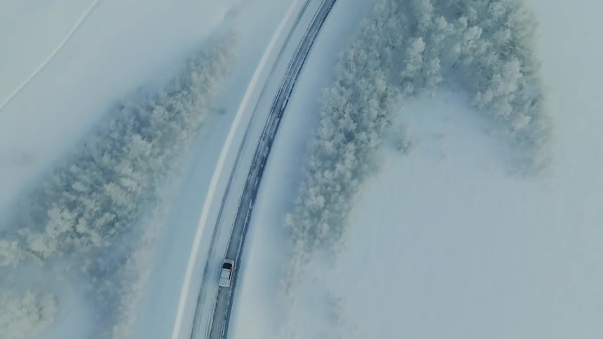 The car travels down the snow covered road