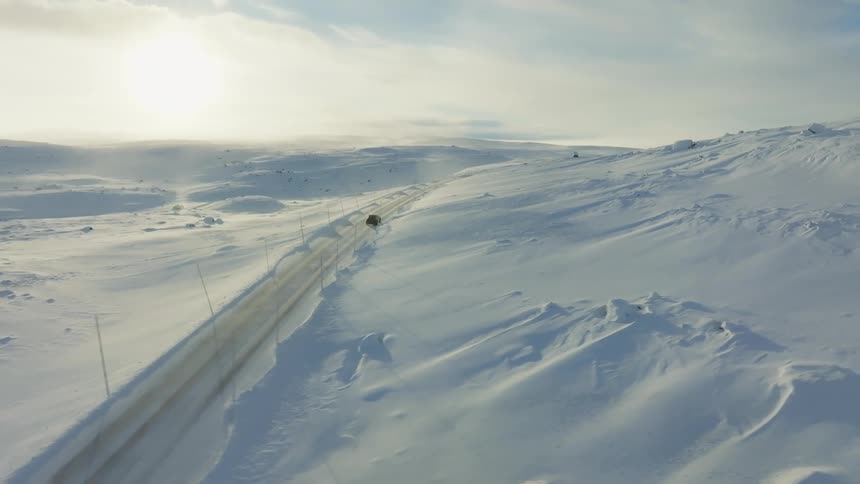 A car drives through the snow filled road
