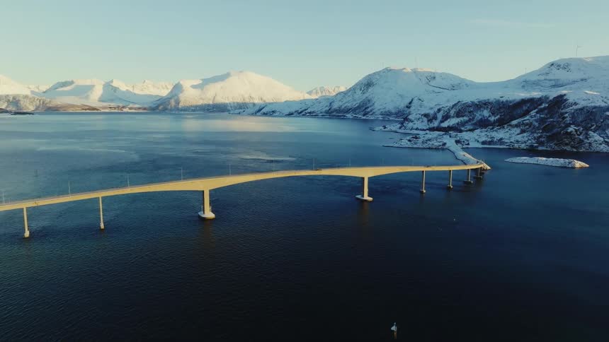 Aerial view of a bridge with snowy mountains
