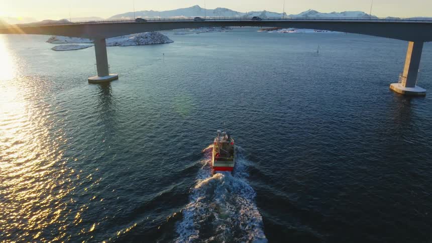 A boat is traveling under the bridge