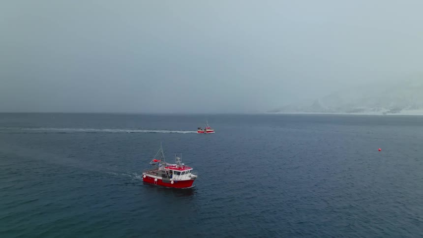 Two red and white boats leave wakes while traveling through oceanwater