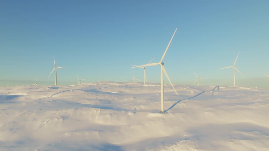 Aerial view of wind turbines on a hill covered in snow