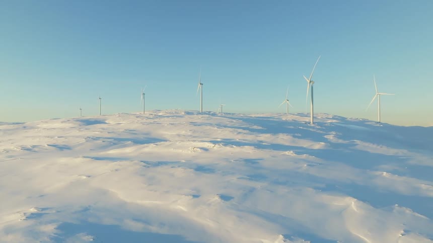 Aerial view of wind turbines on a hill covered in snow