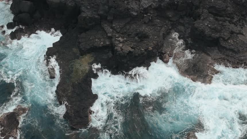 Aerial view of sea water hitting the rocky shore