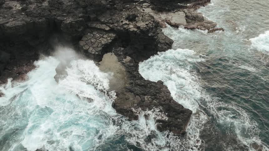 Aerial panorama of strong sea waves hitting the rocky coast during daytime