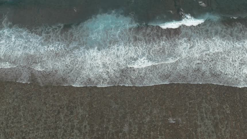 Aerial of ocean waves rolling into the beach in slow motion